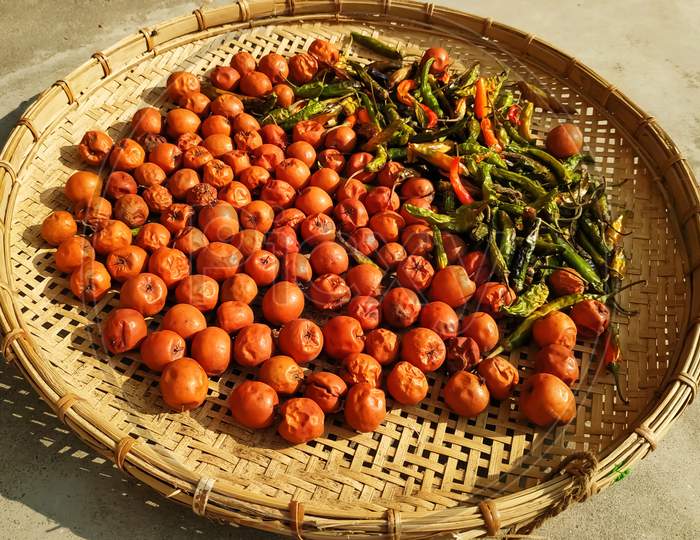 Berries and chillies kept on a bamboo sieve for sun drying