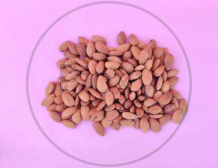 Top View Of Unpeeled Heap Of Almonds Isolated On Pink Background.