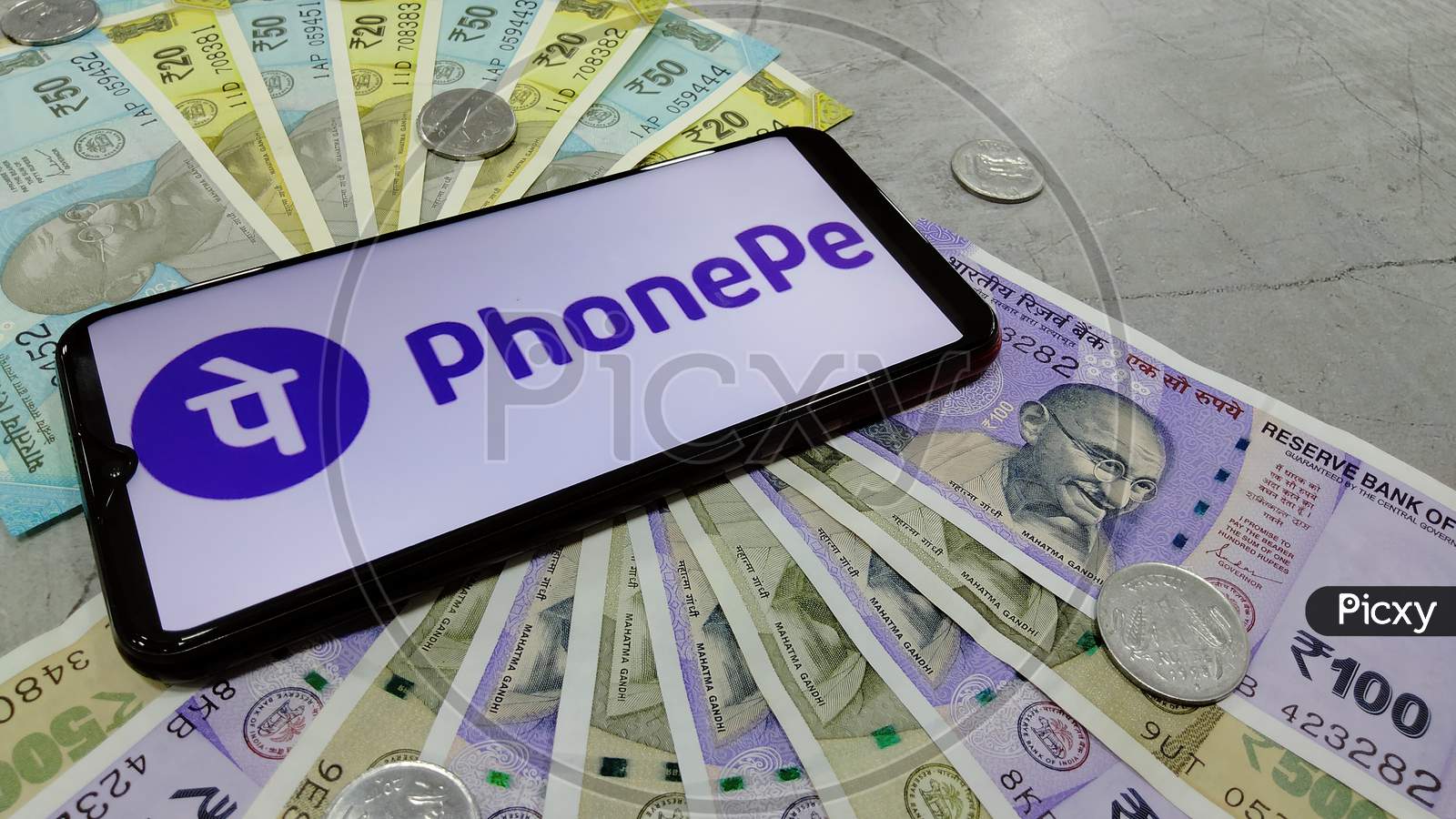 Tamil Nadu, India - January 21 2021: Indian currency notes along with logo of PhonePe on a smart phone