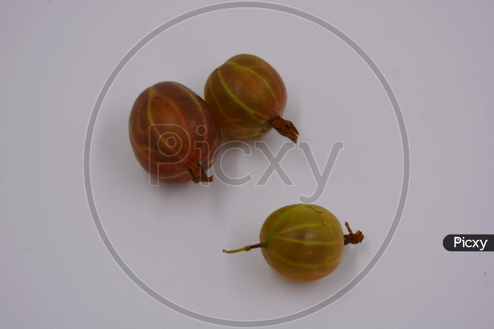 Delicious ripe fruits of red juicy gooseberries arranged in a handful on a white matte background with bright lighting. Useful and healthy food for the human body, delicious sweet and sour fruits.