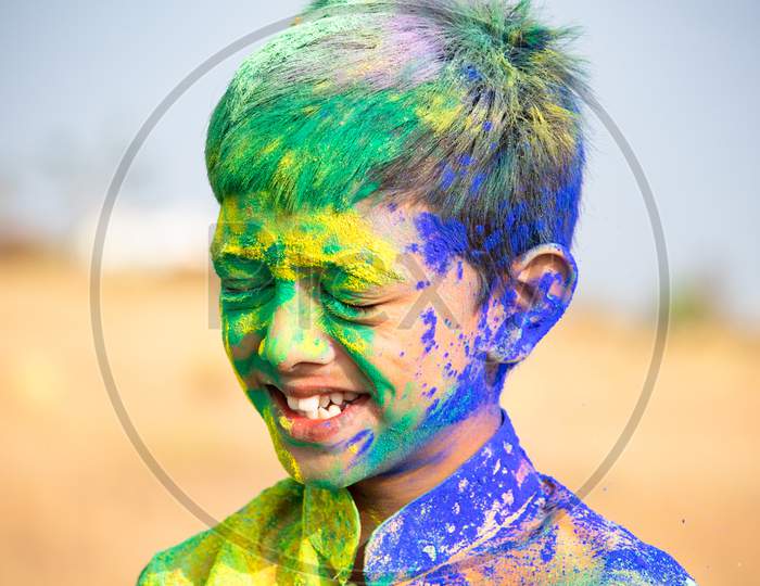 Portrait Of Smiling Young Face Of Kid With Holi Festival Colours Applied.