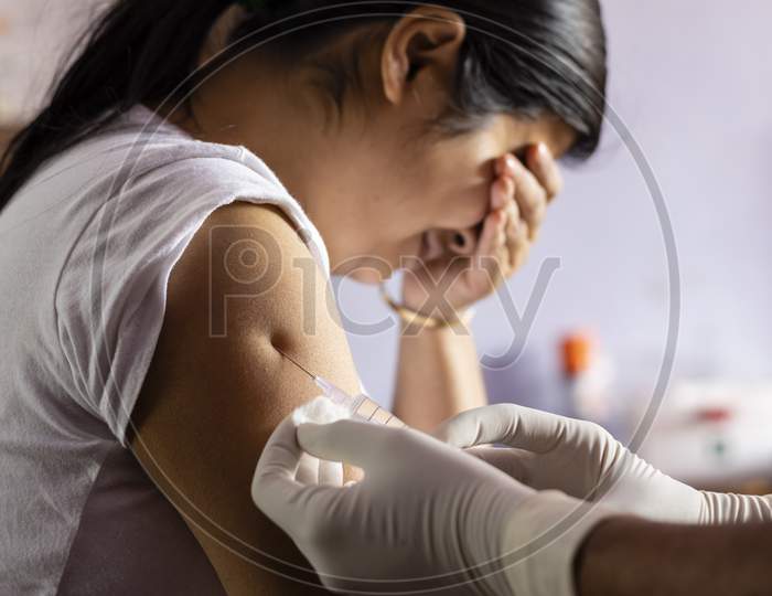 A Pretty Indian Woman Closes Her Eyes While Being Vaccinated