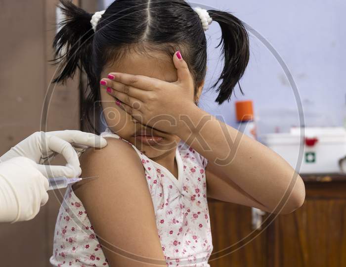 An Indian Girl Child Covers Her Eyes In Fear During Vaccination