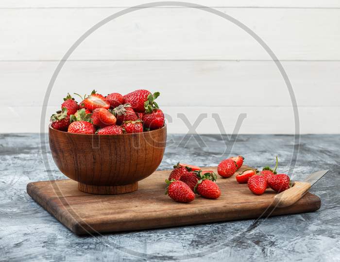 Fresh strawberries in wooden bowl with knife