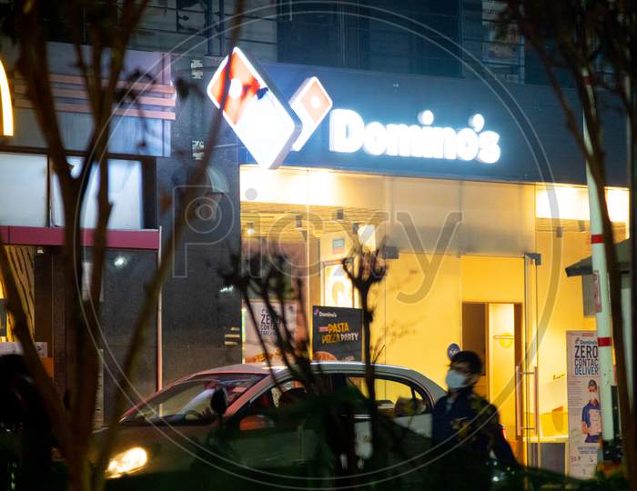 Lit Signboard For A Dominoes And Mcdonalds On A Busy Indian Street With Cars Lining Up For Takeaway From The Fast Food Quick Service Restaurant