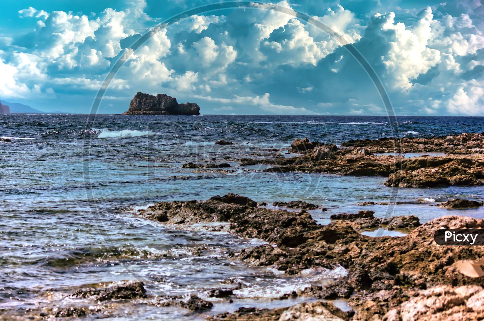 A Landscape View Across The Sea From Imeri Gramvousa To Cape Gramvousa, Kissamos, Crete, Greece Against Dramatic Clouds And Rocky Terrain