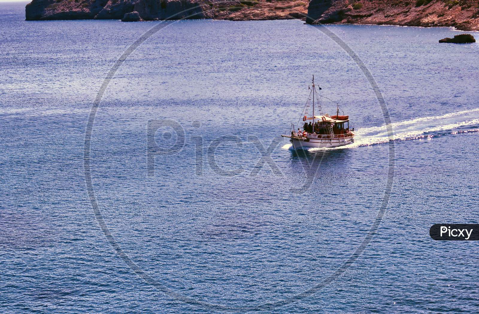 Crete Or Kreta, Greece: A Ship Sailing On Mediterranean Sea Against Rocky Terrain On Spinalonga Island, Formerly Used As A Leper Colony, Near Elounda, Mirabello Gulf