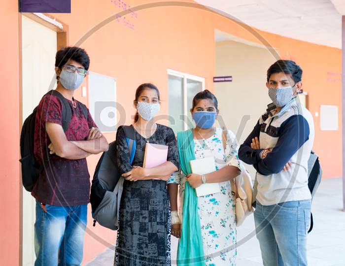 Selective Focus On Girl With Blue Mask, Group Of College Students Standing With Arms Crossed At Corridor With Medical Face Mask Worn During Coronavirus Or Covid-19 Pandemic.