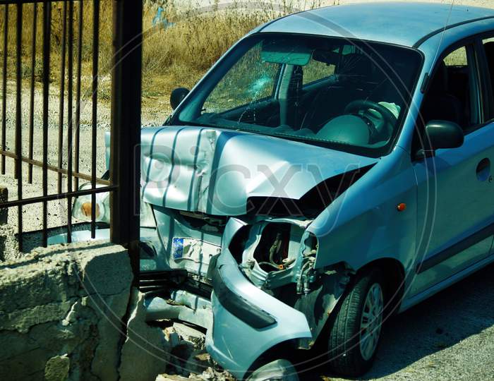 Kreta Or Crete, Greece - September 11, 2017: An Unidentified Abandoned Crashed Car Damaged After Accident Due To Collision With Concrete Fence. Close Up Shot Of A Front Part Of A Car Accident