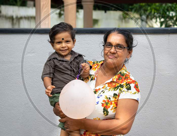 A 1-Year-Old Boy And Her Mother Portrait Outdoor, Mom Holding Her Baby Boy And Both Smiling.