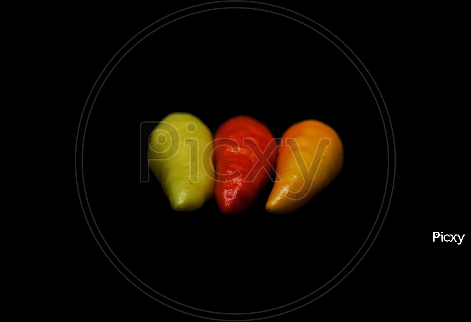 Three Colors Of Chillies In Black Background