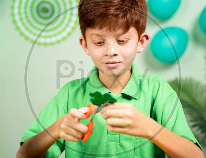 Young Kid Busy In Preparing Shamrock Leaves For Saint Patricks Day Festival Celebrations At Home.
