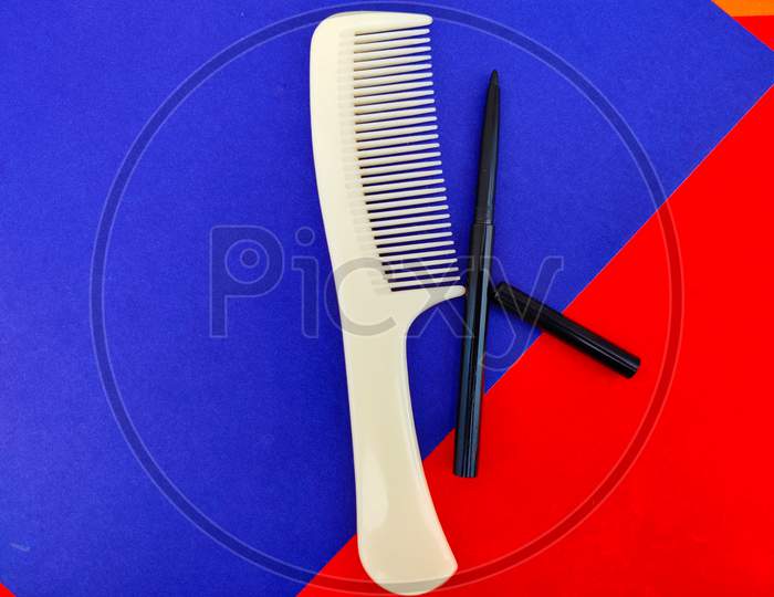One Comb And Kajal Pencil Isolated On Red And Blue Background