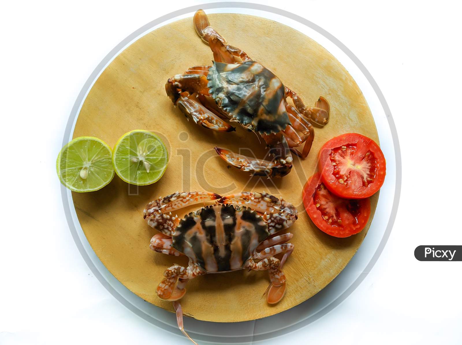 Selective Focus Of Fresh Crucifix Crab On A Wooden Pad,Decorated With Lemon Slice And Tomato Slice . Isolated On A White Background.