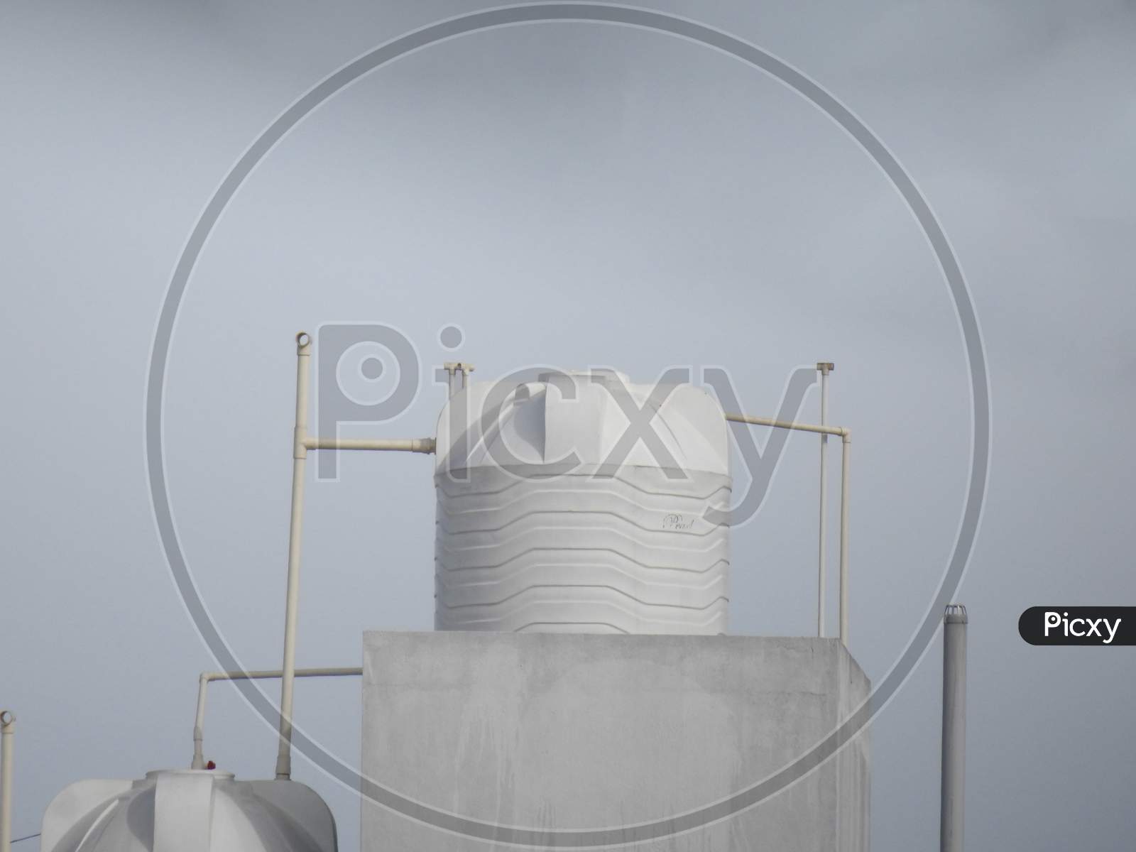 White, Yellow And Black Color Plastic Water Tank At The Top Of The Building In The City