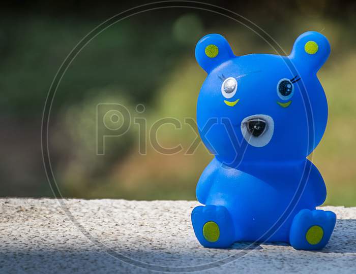 Cute Blue Color Small Bear Toy On The Floor, Blurred Background