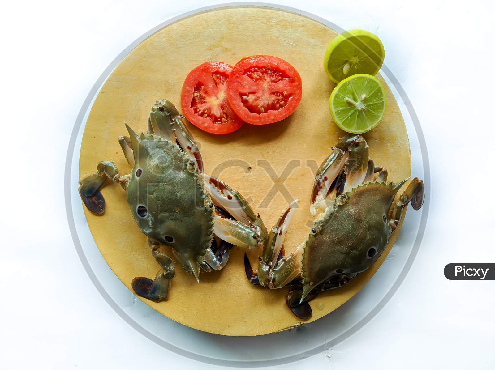 Selective Focus Of Fresh Three Spotted Swimming Crab On A Wooden Pad,Decorated With Lemon Slice And Tomato Slice . Isolated On A White Background.