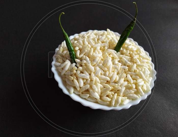 Puffed rice and green chilli on black background.