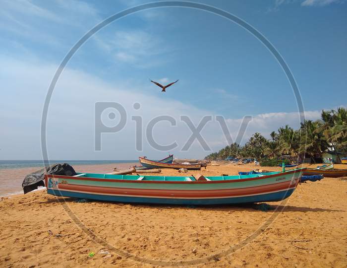 Fishing boat on the seashore, blue sky and flying eagle