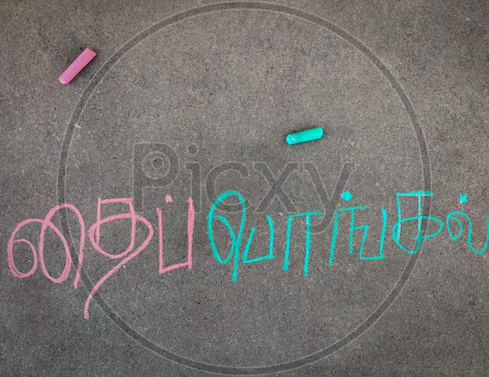 The Inscription Text On The Grey Board, "Thai Pongal " In Tamil Letters. Using Color Chalk Pieces.