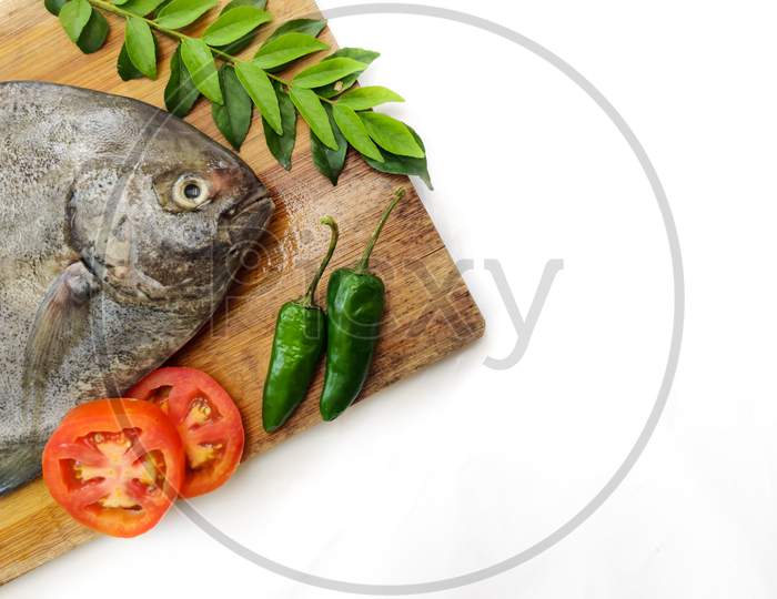 Fresh Black Pomfret Fish Decorated With Herbs And Vegetables On A Wooden Pad,Selective Focus.Space For Text.