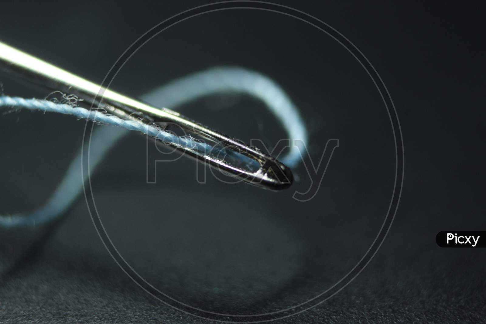Small Needle With Thread In The Eyelet, Isolated Over The Black Background.
