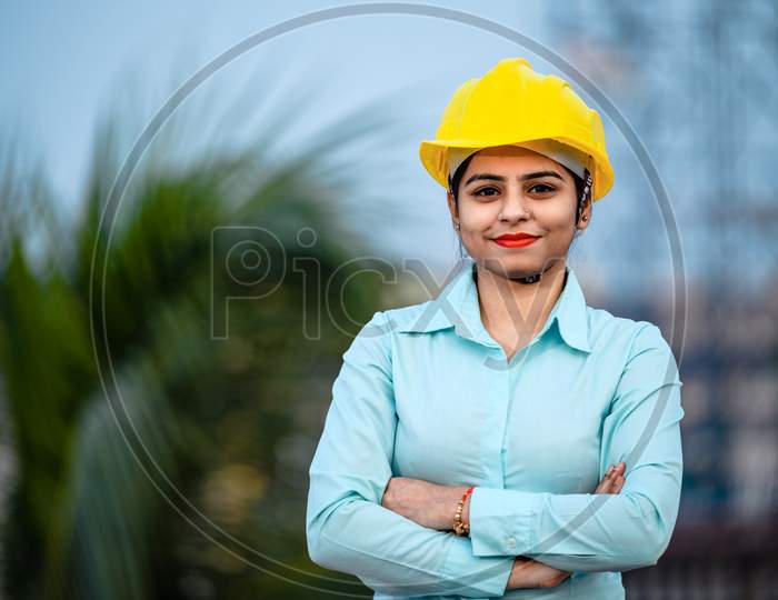 Close Up Portrait Of Beautiful Female Engineer Wearing A Protective Helmet And Looking At Camera.