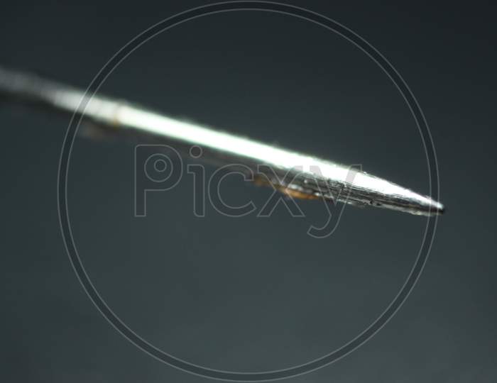 Macro Photograph Of Sewing Needle Over The Black Background.