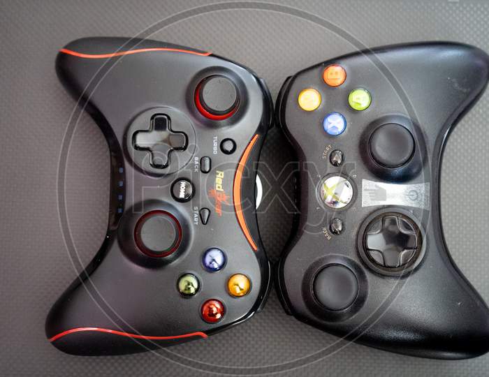 Redgear Vs Xbox Controller On A Carbon Fiber Background Showing Technology Of Inputs For Computer Gaming