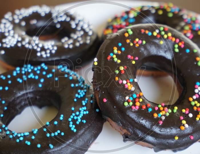 Colorful chocolate glazed donuts with sprinklings