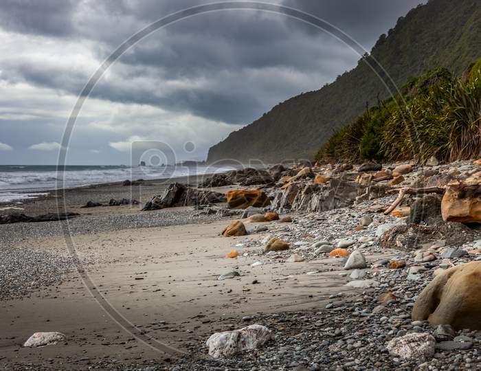 Stormy Weather Approaching A Rock Strewn Beach In New Zealand