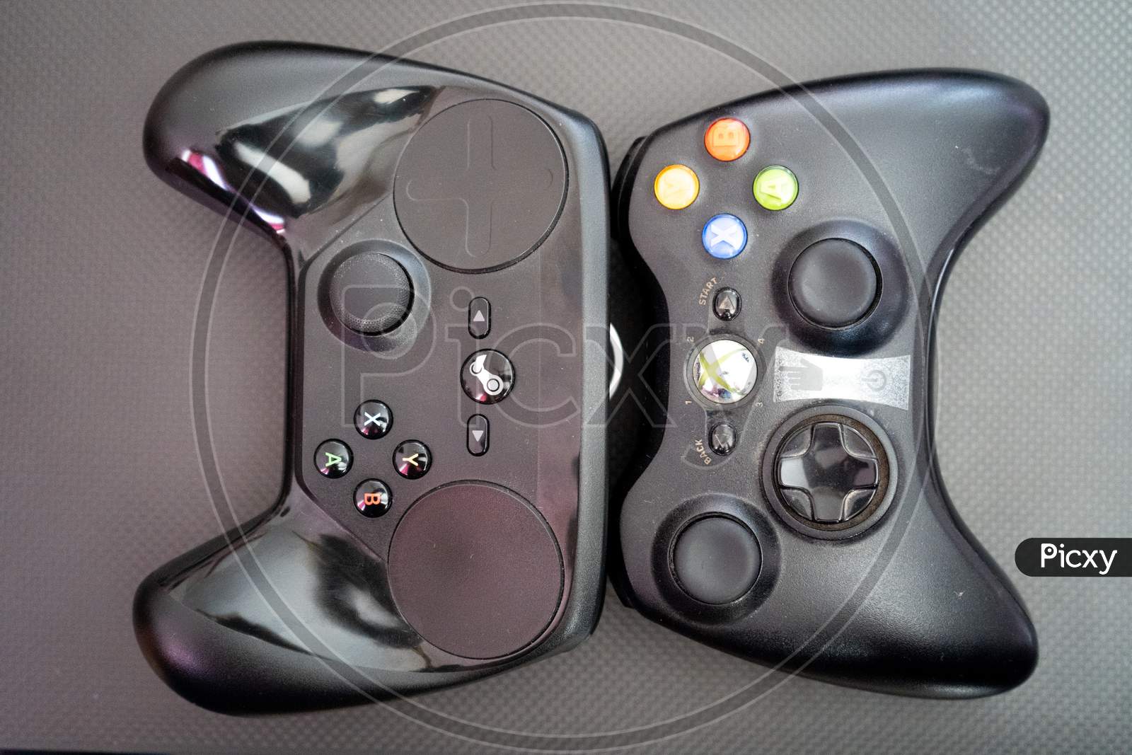 Xbox Vs The Steam Controller On A Carbon Fiber Background Showing Technology Of Inputs For Computer Gaming