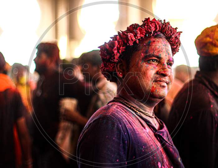 Mathura, Uttar Pradesh/ India- January 6 2020: Portrait Of A Man With His Face Covered In Holi Colors With A Crown Made From Flowers On His Head.