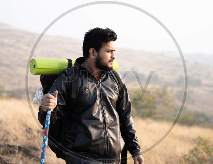Traveller With Backpack Hiking The Mountain By Holding Stick In Hand - Concept Of Solo Hiking Or Trekking.