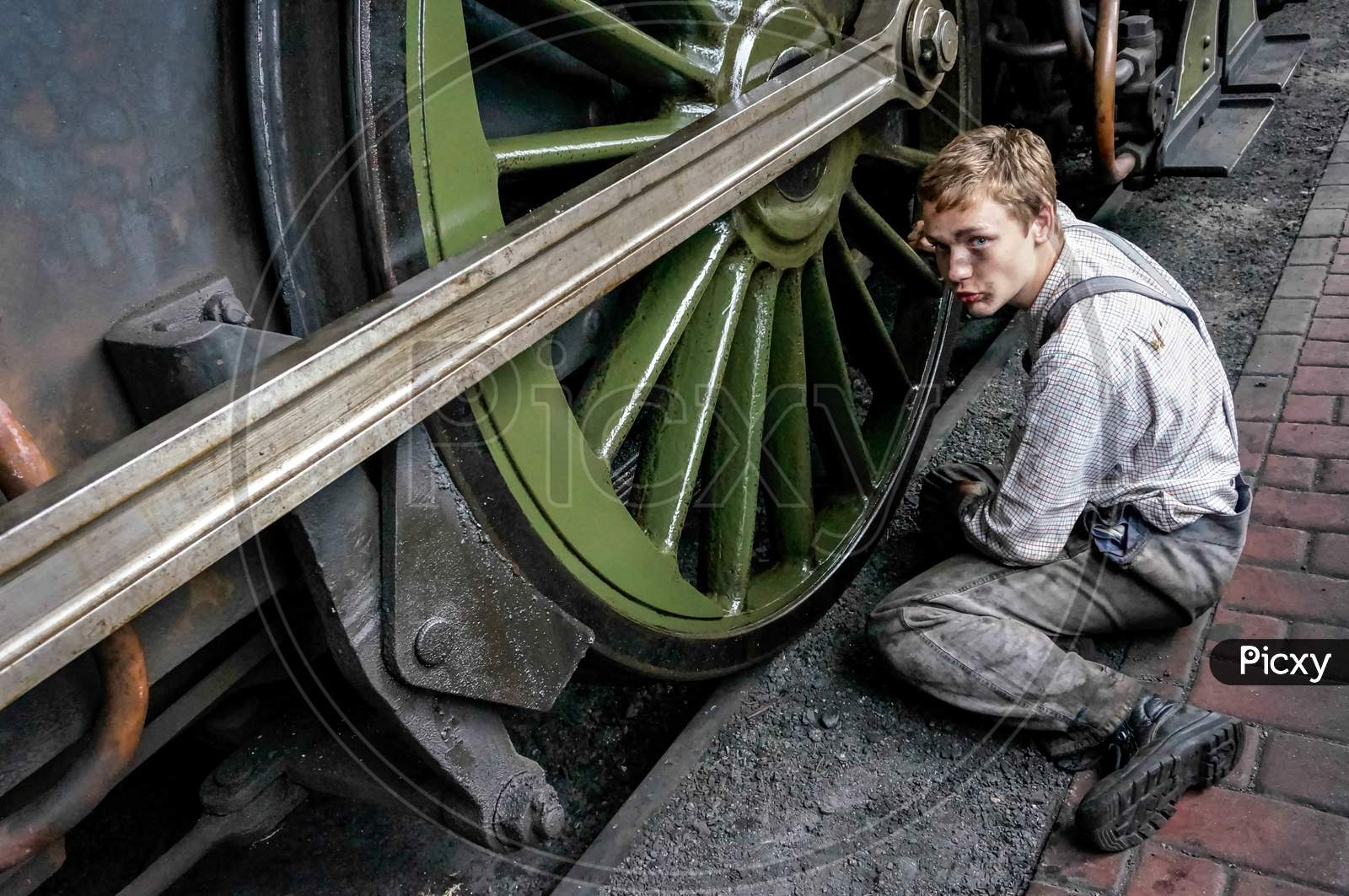 Young Man Cleaning A Steam Train Wheel