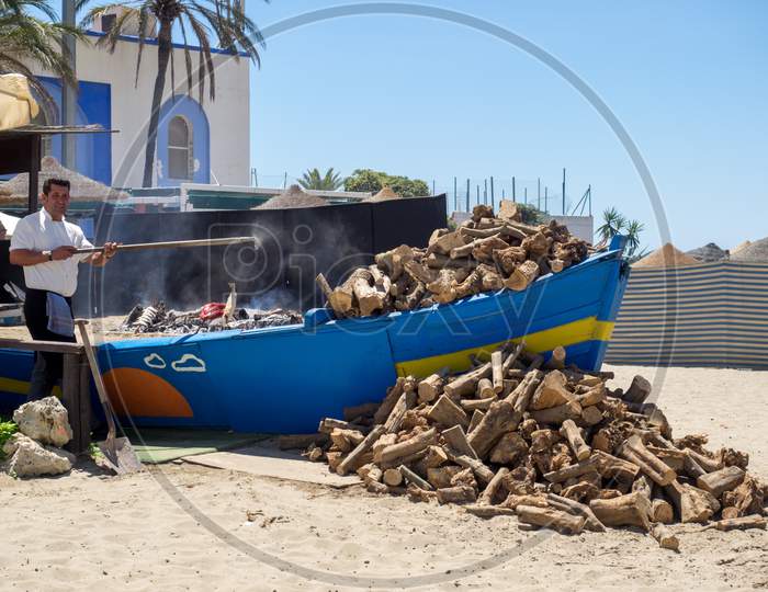 Man Cooking Fish On The Beach In Marbella