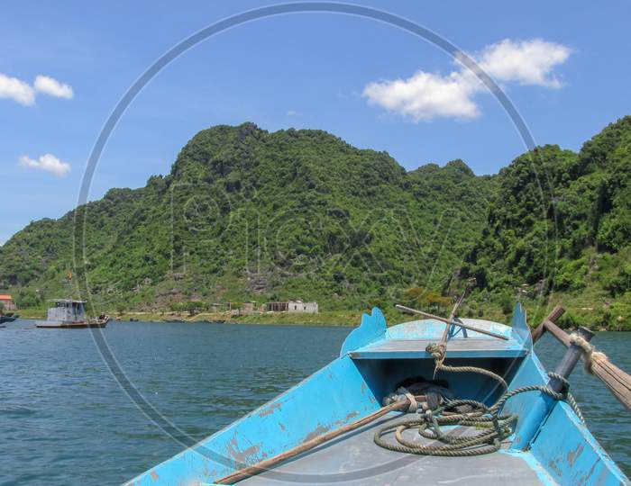 Looking At The Blue River And High Mountain From The Bow Of A Small Wooden Boat In Phong Nha - Ke Bang National Park, Ninh Binh Province, Vietnam