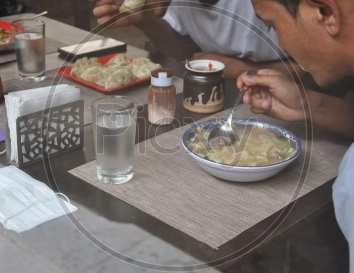 People eating tibetan food at indoor cafe seen through window glass