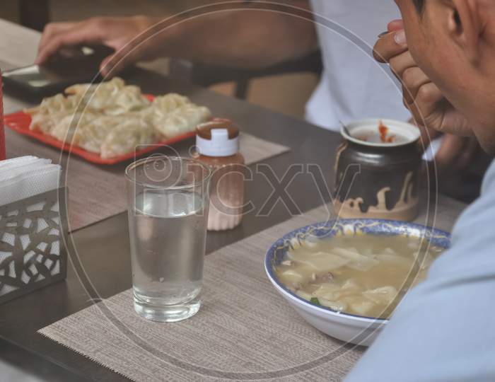 Selective focus of people eating tibetan food at indoor fast food cafe seen through window glass