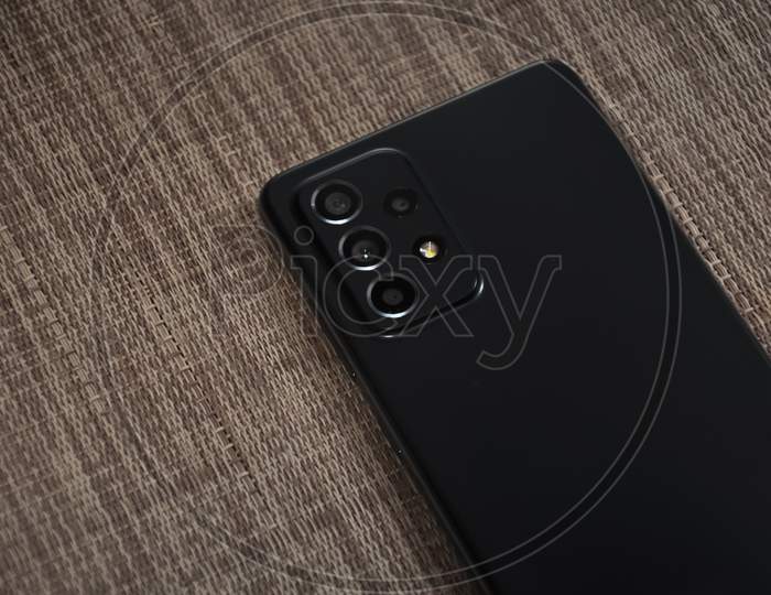 Back side of black color mobile phone (smartphone) over textured background