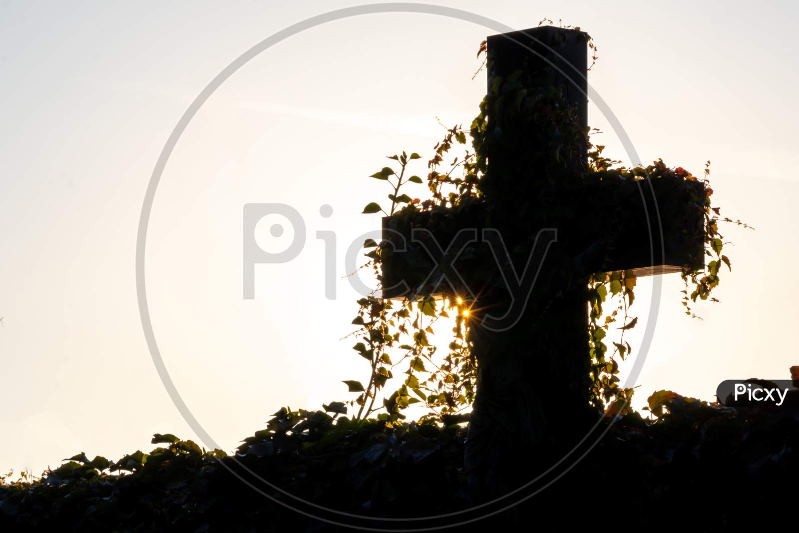 Glowing cross silhouette with sunbeams sunset sunlight and clear evening sky shows christianity spirituality of church and forgiveness at grave and death for catholic resurrection metaphors on easter