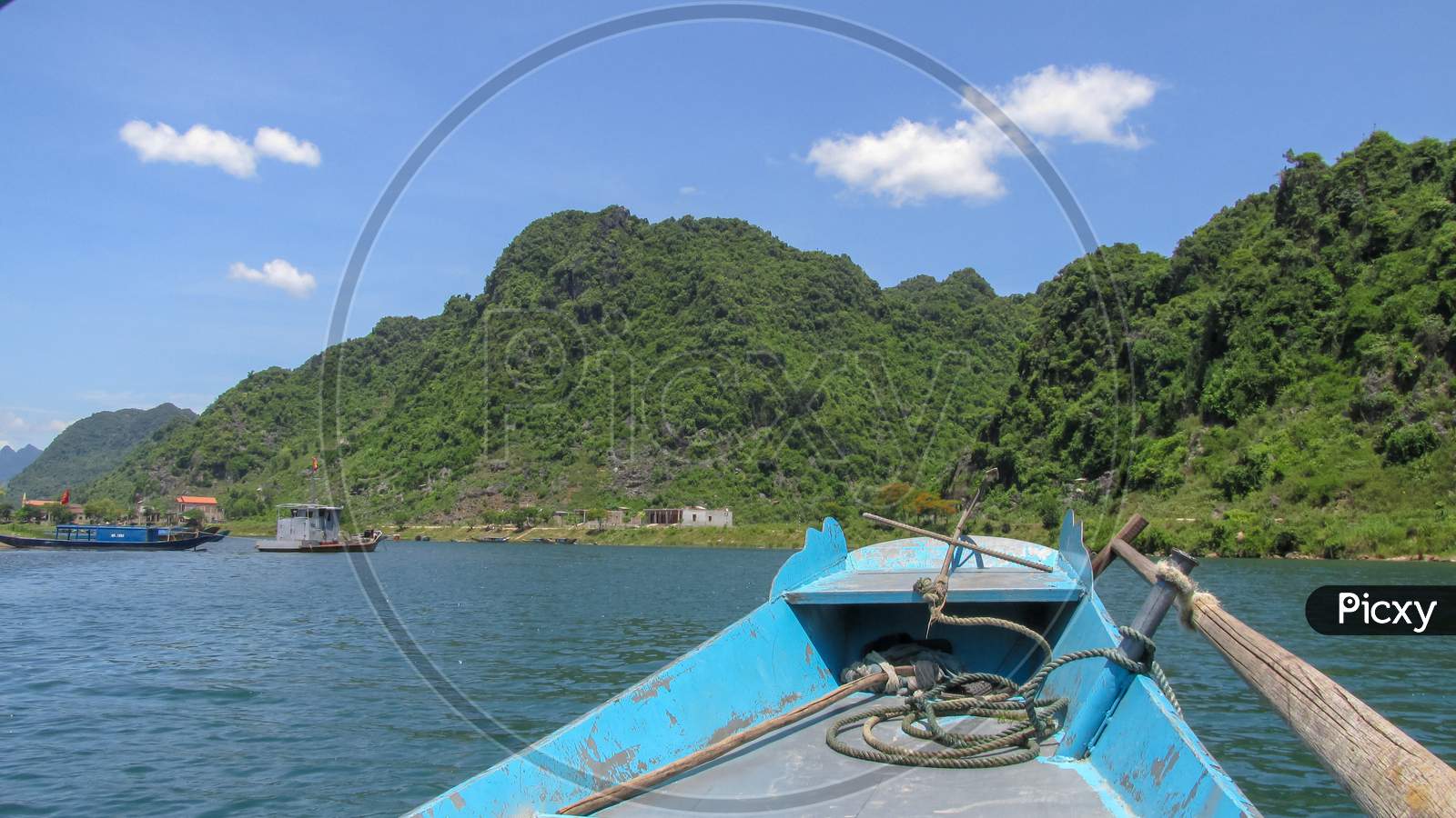 Looking At The Blue River And High Mountain From The Bow Of A Small Wooden Boat In Phong Nha - Ke Bang National Park, Ninh Binh Province, Vietnam