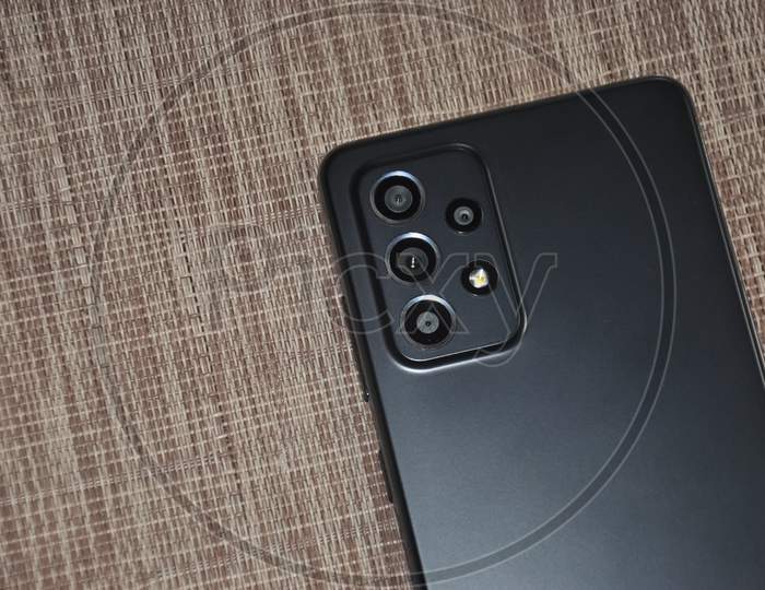 Back side of black color mobile phone (smartphone) over textured background