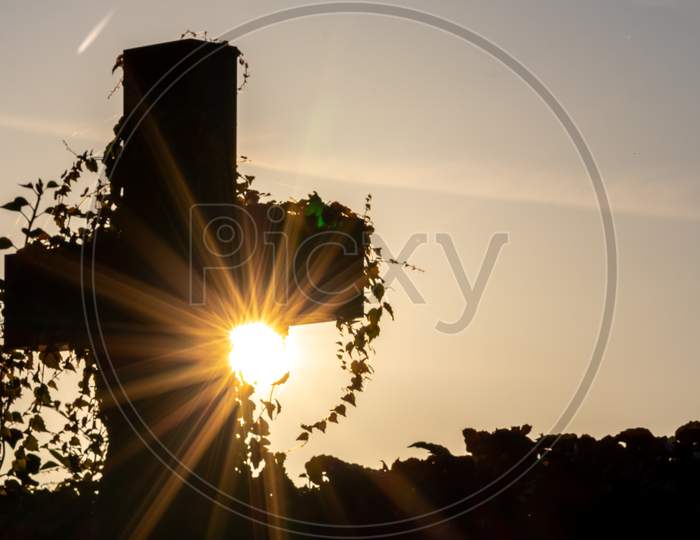 Glowing cross silhouette with sunbeams sunset sunlight and clear evening sky shows christianity spirituality of church and forgiveness at grave and death for catholic resurrection metaphors on easter