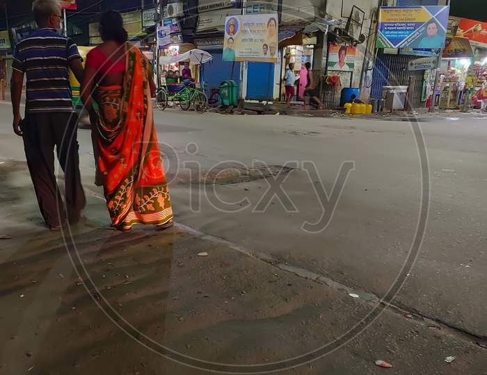 A old couple walk on a busy road in kolkata during Durga puja.