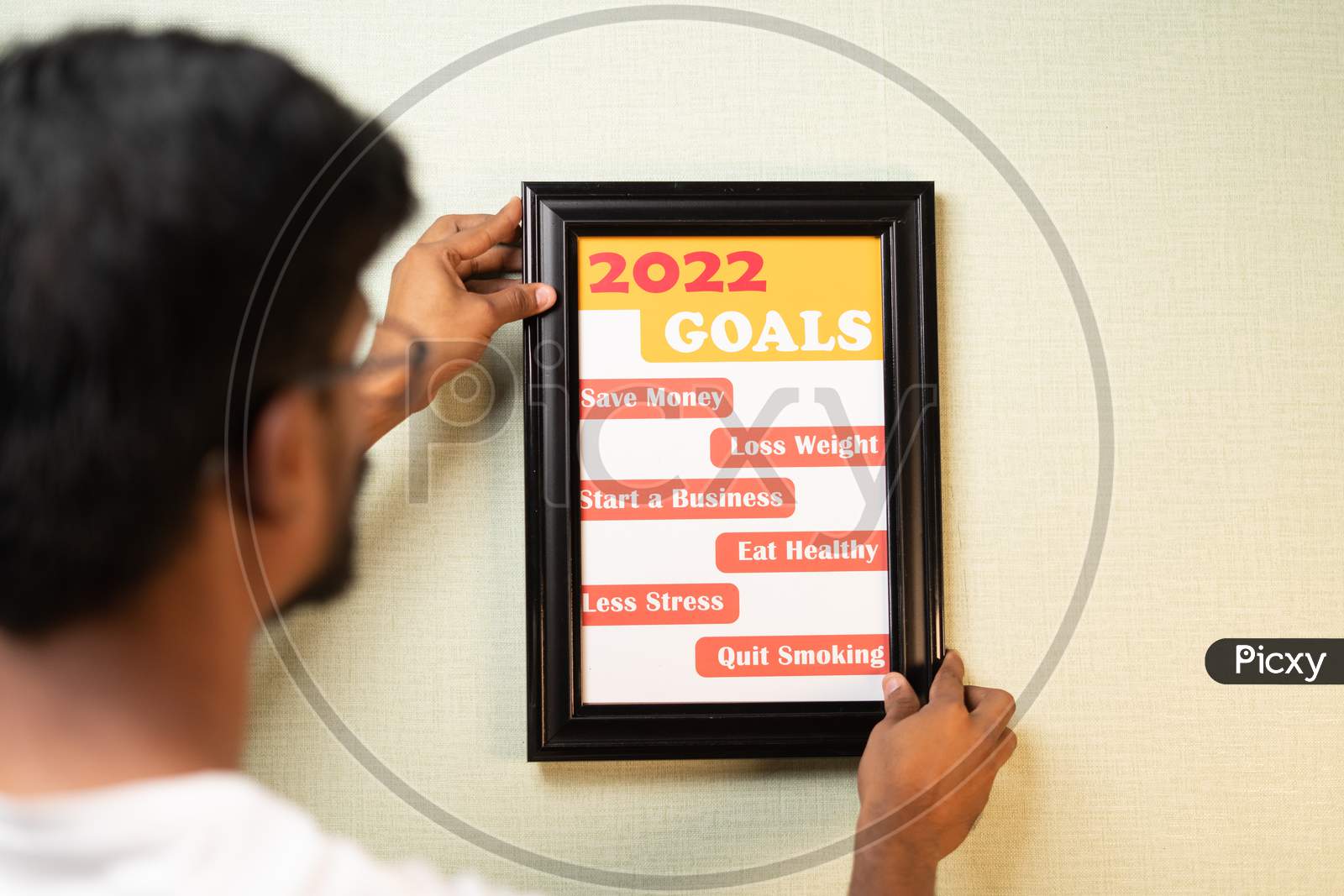 Shoulder Shot Of Young Man Placing 2022 Goals On Wall - Concept Of New Year Goal Setting.