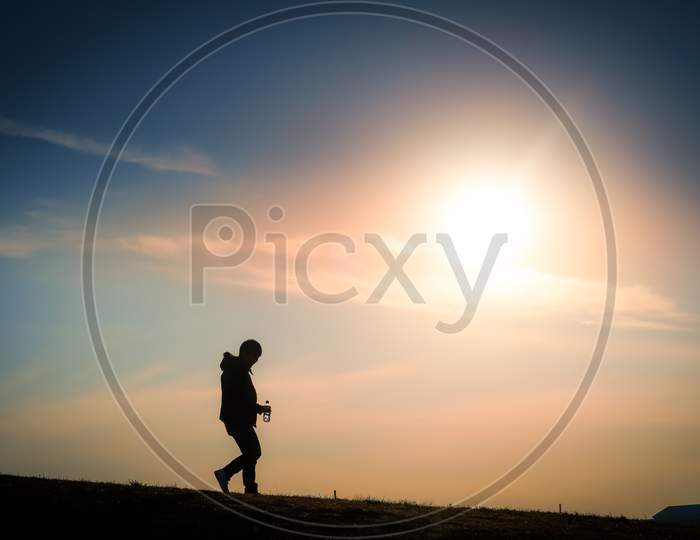 Silhouette Of A Man Standing In The Twilight Of The Hill