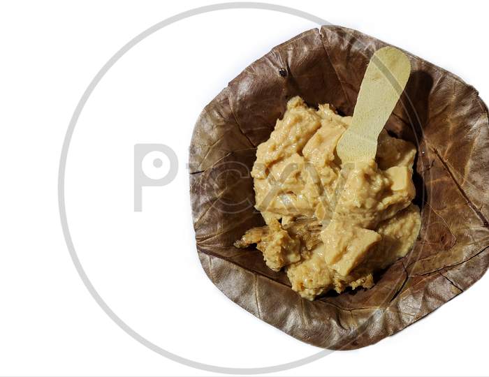 Mishti Doi or Sweet Yogurt a traditional fermented sweet of West Bengal, India in saal pata or sal leaf bowl with wooden spoon isolated on white background, street food