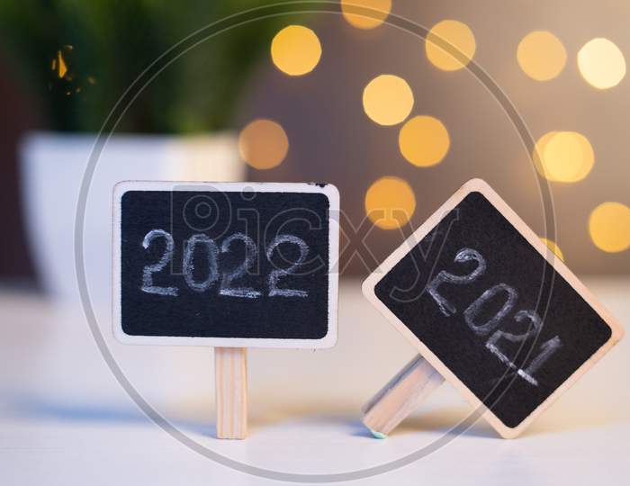 Closeup Shot Of New Year 2022 Sign Board With Fallen 2021 Sign Board On Decorated Background - Concept Of Welcoming New Year Or End Of 2021.