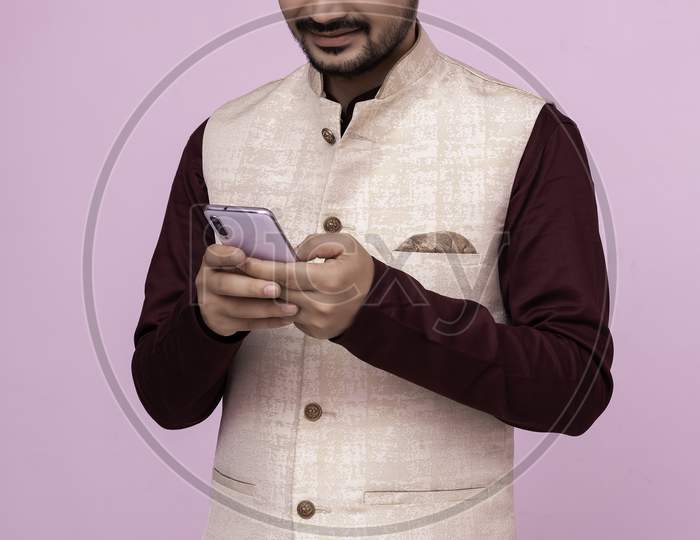 Asian Young Indian Boy Wearing Traditional Dress Texting On A Smartphone. Smile On Face.